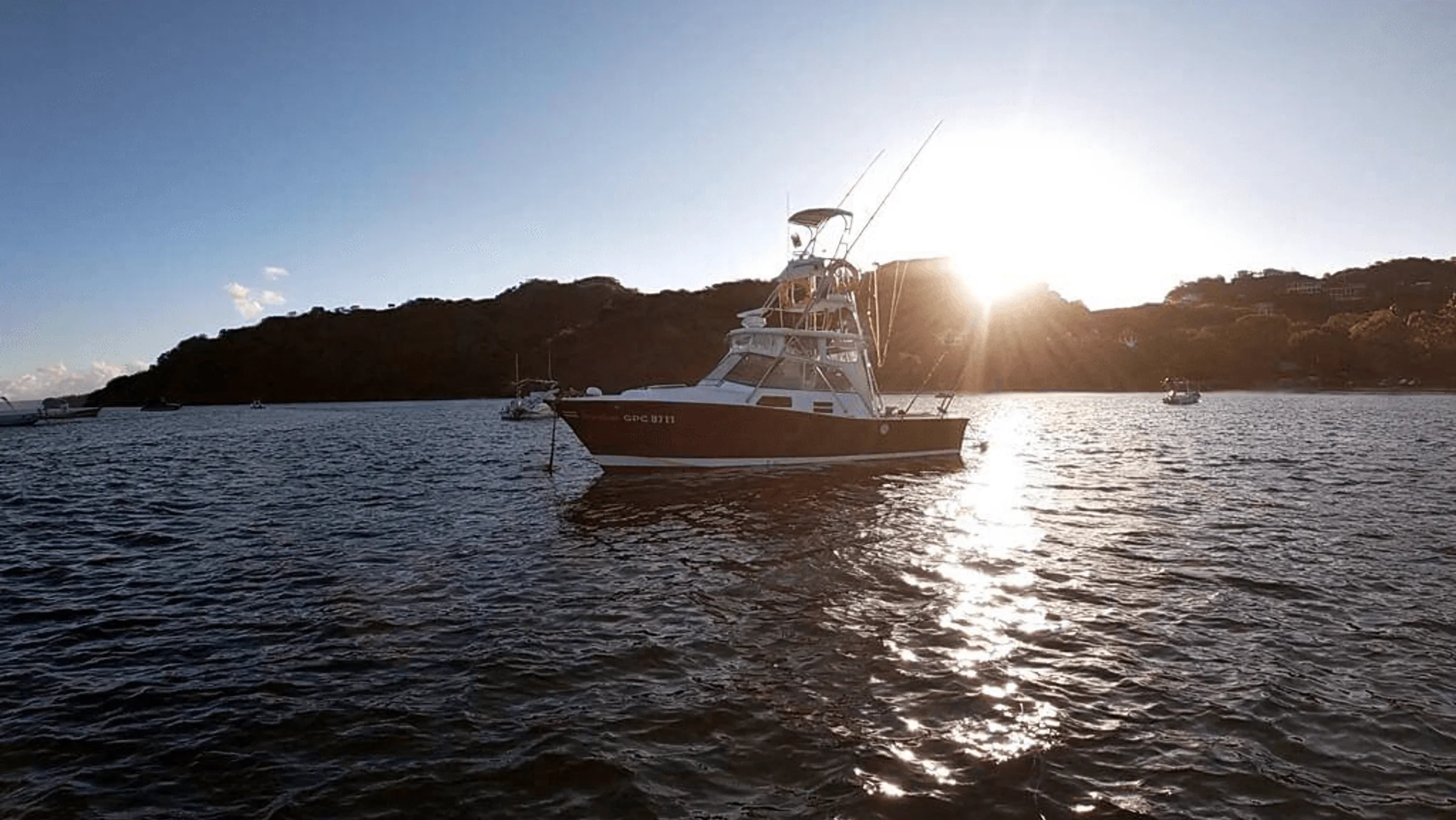 The Freedom anchored off Playa Flamingo with the sun going down behind the headland